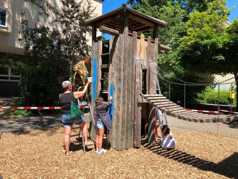 Kinder bemalen Kletternturm mit blauer Farbe