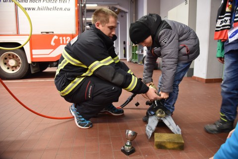 Kind probiert zusammen mit einem Feuerwehrmann das Schneidgerät aus