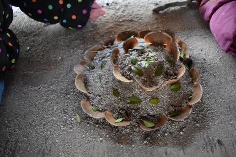 Eine Torte aus Sand verziert mit Tannenzapfen und Blättern 