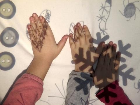 Kinderhände versuchen projizierte Schatten zu greifen.