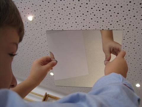 Ein Kind sammelt Erfahrungen mit einer Spiegelfliese