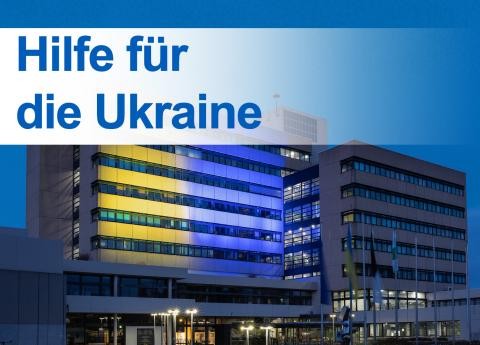 Ein Gebäude in gelb blauer Beleuchtung mit Schrift "Hilfe für die Ukraine"