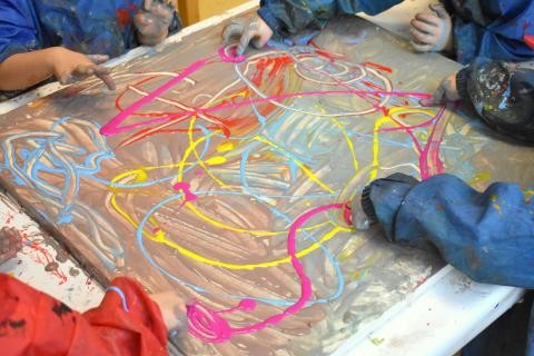 Kinderhände vermischen Farben auf einer Leinwand 