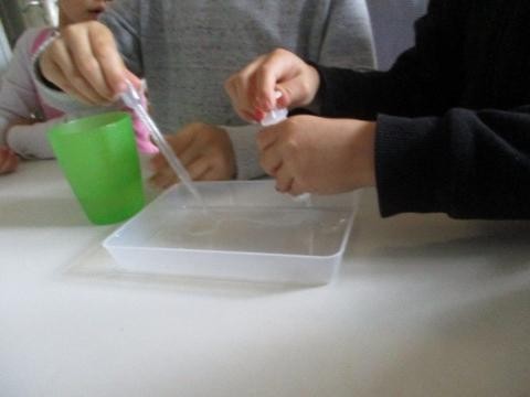 Zwei Kinder experimentieren mit Wasser und Pipetten