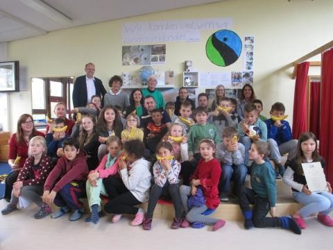 Gruppenbild mit Dr. Bernd Vöhringer. Die Kinder halten faire Bananen in ihren Händen.