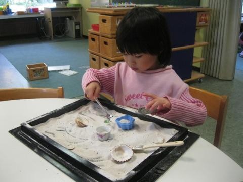 Ein Kind füllt verschiedene Formen mit Sand