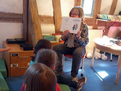 Die Bibliothekarin zeigt den Kindern ein Bilderbuch 