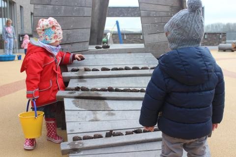Zwei Kinder verteilen Tannenzapfen auf einer Rampe