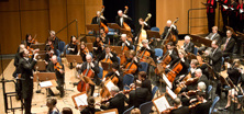 Menschen spielen Instrumente in Orchester mit Dirigent