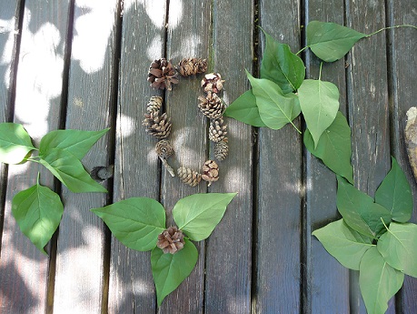 Kreative Legearbeit mit Blättern und Zapfen im Garten der KiTa