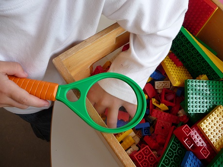 Ein Kind greift in eine Kiste mit Legosteinen